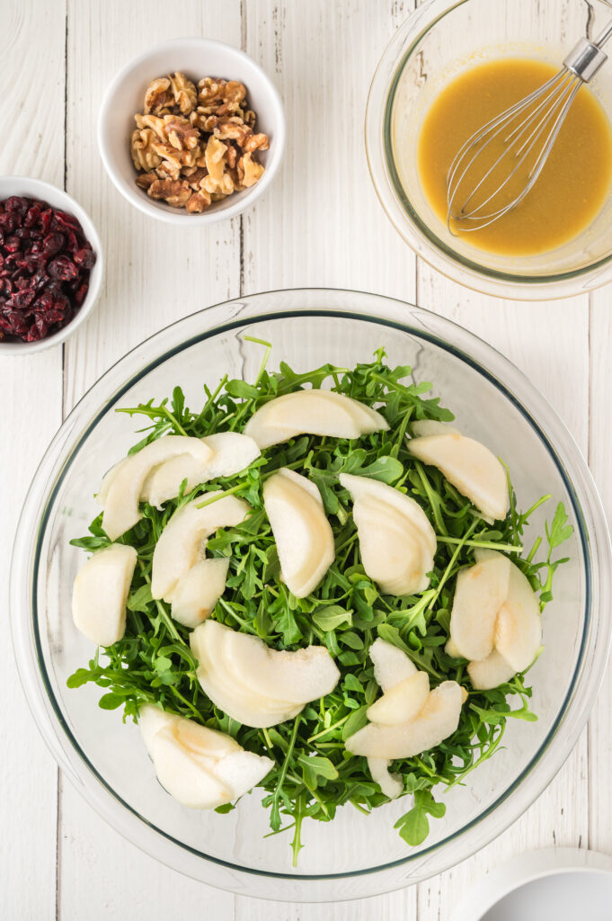 arugula pear salad in a clear bowl