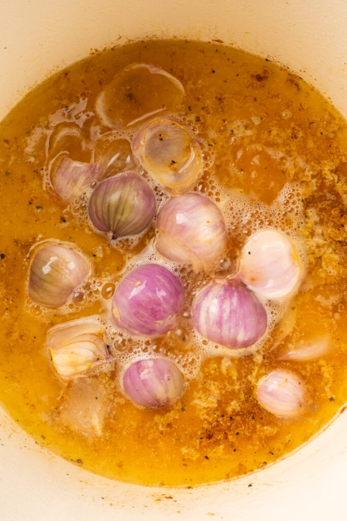 shallots and garlic in a Dutch oven with chicken stock