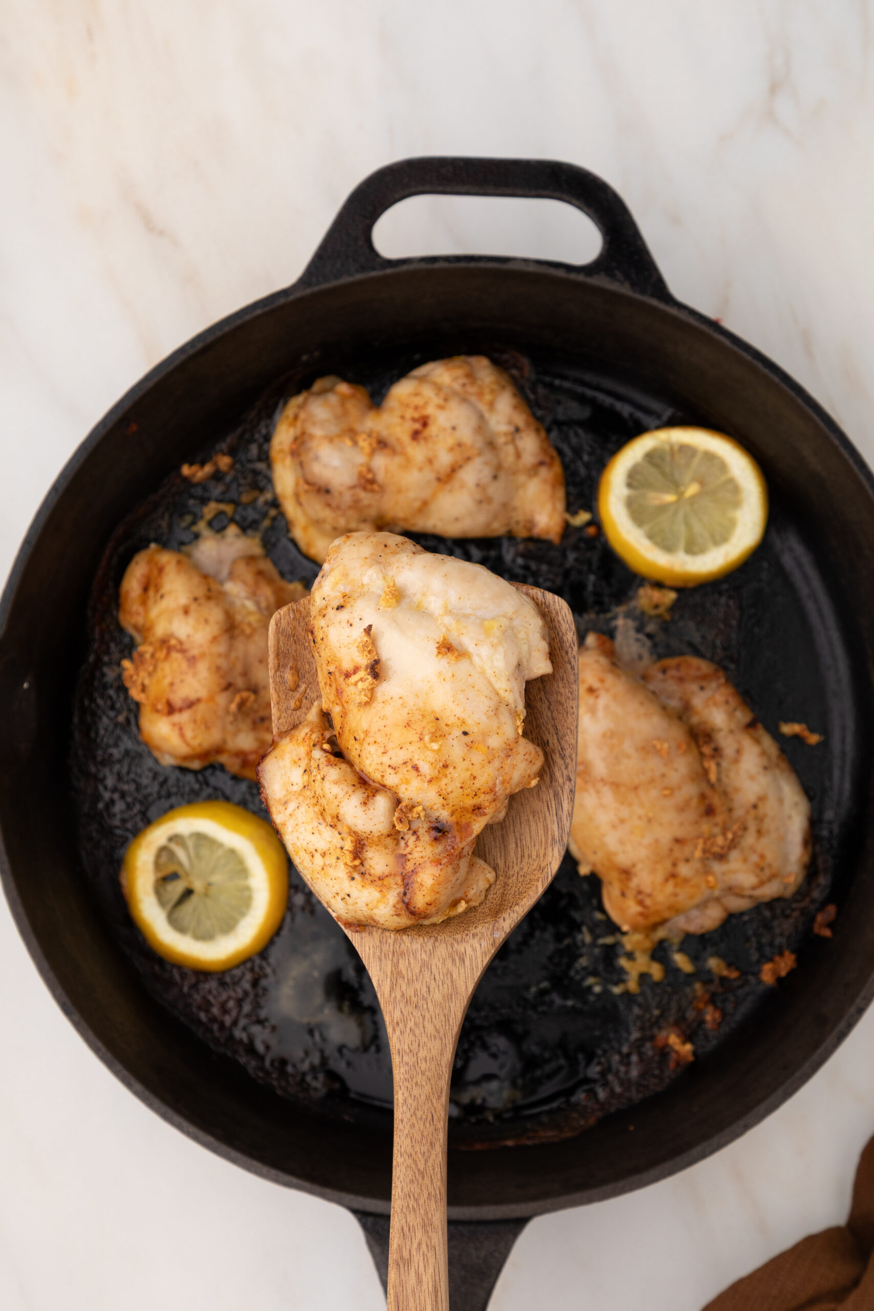 Juicy skinless chicken thighs baked with lemon and herbs in a cast iron skillet