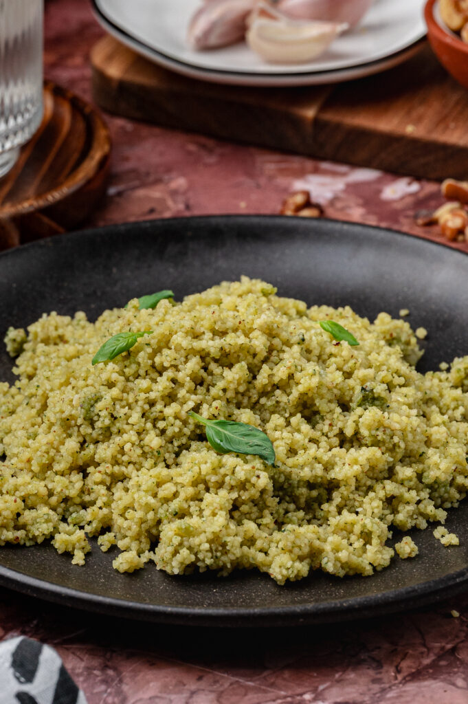 Close-up of couscous coated in green basil pesto