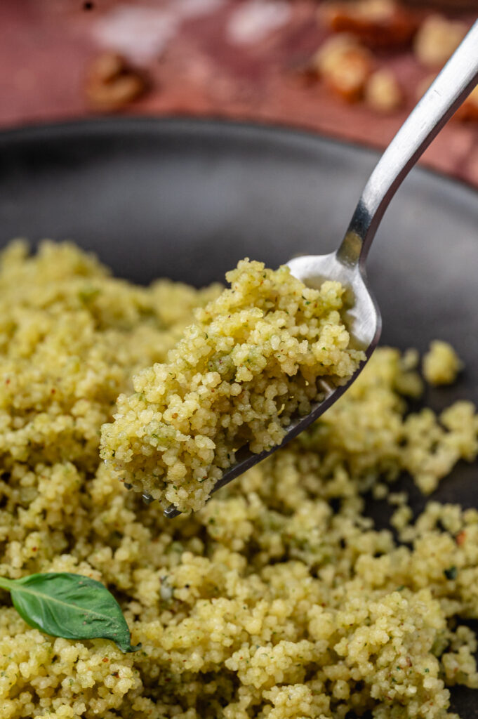 Close-up of couscous coated in green basil pesto
