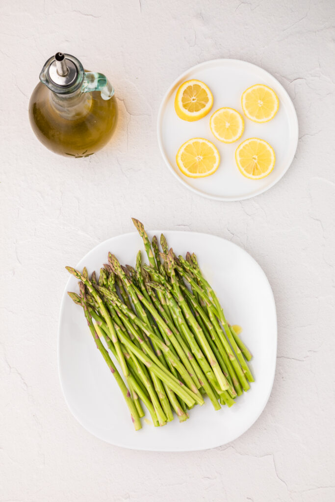 asparagus on a white plate and lemons